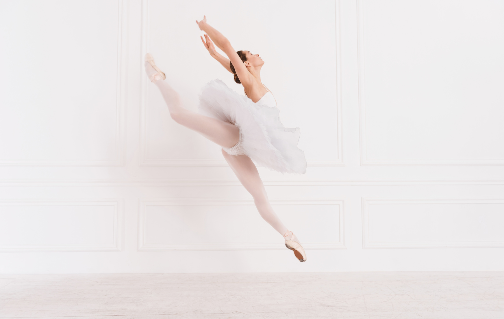 Tender ballerina jumping over white background